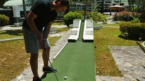 Man playing mini-golf on green course on sunny day Видео 271199149