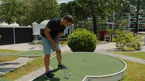 Man playing mini-golf outdoors on sunny day with focus on leisure Stock Footage 271199183