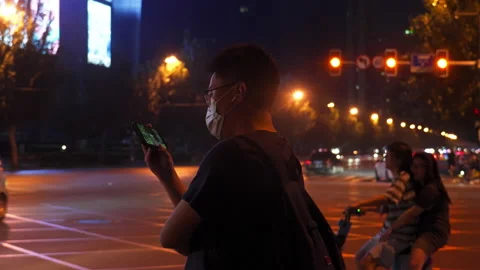 Man playing mobile phone on the side of the road at night Stock Footage 237614516