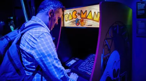Man playing with pac-man arcade machine Stock Photos