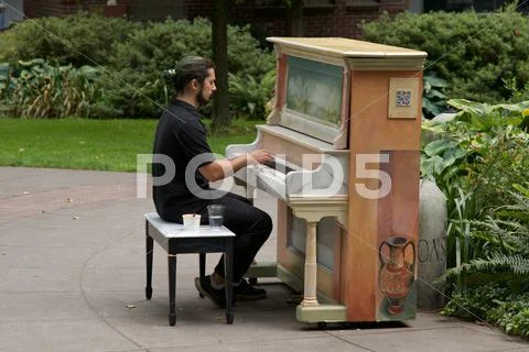 A Man Playing A Piano Installed In A Public Park.