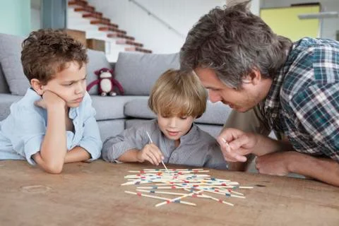 Man playing pick up sticks with his sons Stock Photos