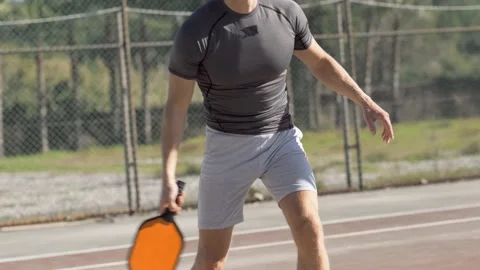 Man playing pickleball game, hitting pickleball yellow ball with paddle, outdoor Stock-Footage 229319318