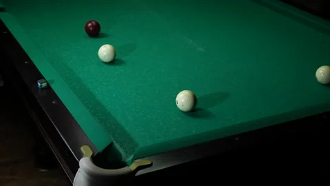 Man playing pool in a dark bar, he hits a white ball with a cue. Playing Stock Footage 240736875
