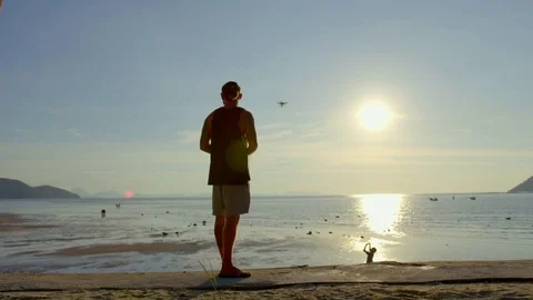 Man playing with quadcopter drone on beach during sunset Stock-Footage 74774877