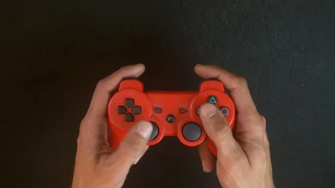Man playing on a red PlayStation controller Stock Footage 92523439