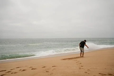 Man playing in the sand at the beach Stock Photos