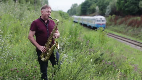 Man Playing Saxophone With Train Moving In The Background Stock Footage 91867415