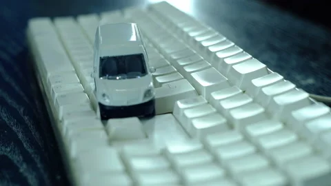 A man is playing a small white car on computer keyboard. Stock-Footage 130477559
