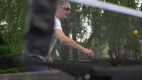 Man playing table tennis. Ping-pong player hit the ball through the net. Slowmo Stock Footage 130666096
