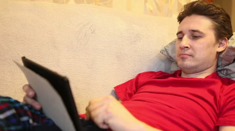 Man playing tablet lying on the couch Stock Footage 60423232