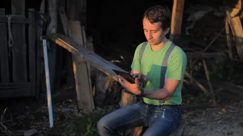 A man playing on a tablet at the sawmill. sunset time Stock Footage 64776782