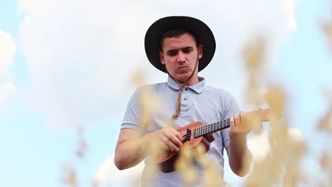 A Man Playing the Ukulele. A Fun Singer and Guitarist Under a Blue Sky and .. Stock Footage 316327400
