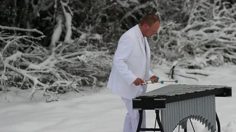 Man playing the vibraphone in snow with white suit Stock Footage 104460513