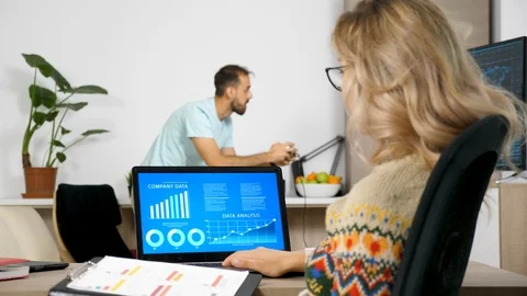 Man playing a video game on the console while her partner is working on the Stock Footage 95124675