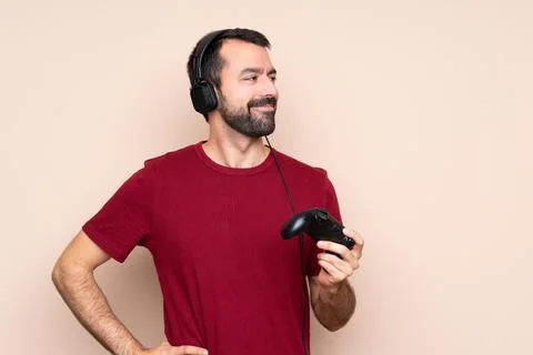 Man playing with a video game controller over isolated wall posing with arms  Stock Photos