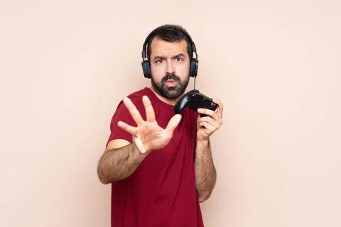 Man playing with a video game controller over isolated wall nervous stretchin Stock Photos