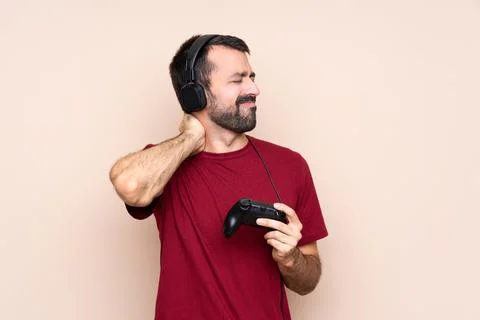 Man playing with a video game controller over isolated wall with neckache Stock Photos