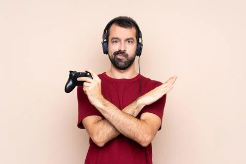 Man playing with a video game controller over isolated wall making NO gesture Stock Photos
