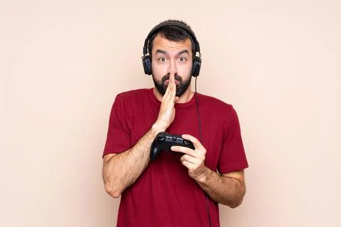 Man playing with a video game controller over isolated wall keeps palm togeth Stock Photos