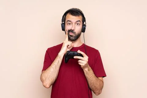 Man playing with a video game controller over isolated wall Looking front Stock Photos