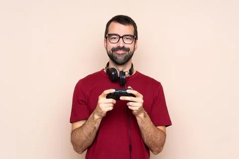 Man playing with a video game controller over isolated wall with glasses and  Stock Photos