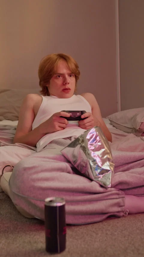 Man Playing Video Game with Gamepad Eating Snacks in Bedroom Stock Footage 346601537