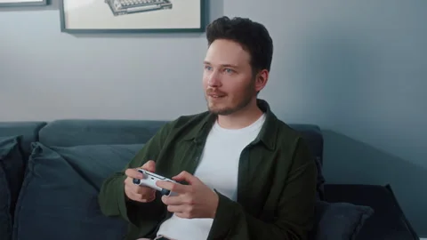 Man playing video game on sofa with controller at home Video stock 319544685