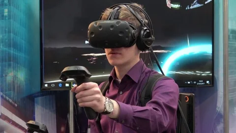 Man playing video game in virtual reality headset and handheld controllers Stock Footage 74145166