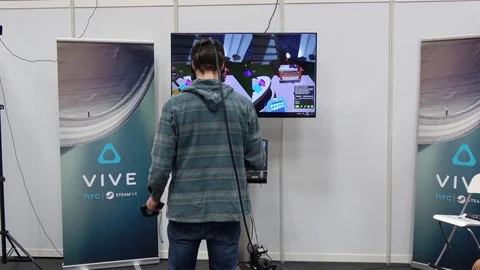 Man playing video game in virtual reality headset and handheld controllers Stock Footage 74364880