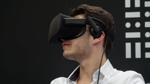 Man playing video game in virtual reality headset and handheld controllers on Stock Footage 76876375