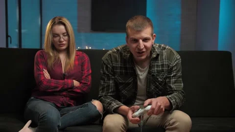 Man playing video games while his girl is getting mad at him and bored in their Stock Footage 225655509