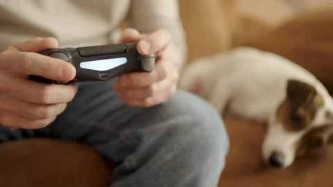 Man Playing Video Games while Petting Jack Russell Terrier on Sofa. Close-u.. Vídeo Stock 331971548