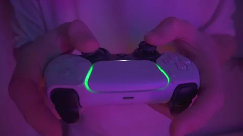 Man is playing a videogame on a console and holding a joystick.  Stockbeeldmateriaal 274350879