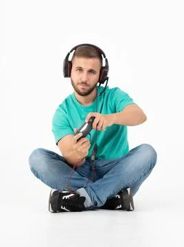Man playing videogames with a controller and a headphones in a white background Фото