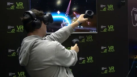 Man playing virtual reality game in HTC Vive VR headset with accessories Stock Footage 81002455