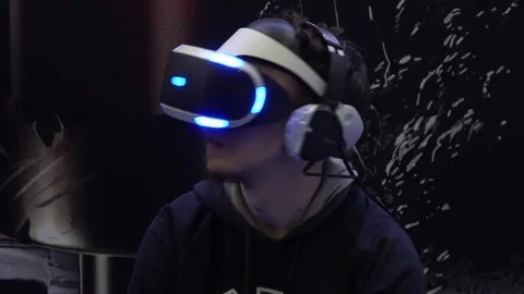 Man playing virtual reality game in Sony VR headset with accessories controllers Stock Footage 81512904