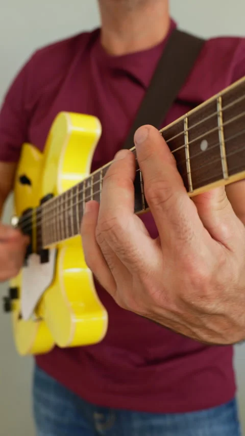Man playing a yellow guitar, selective focus. No faces shown, vertical video Stock Footage 217728205