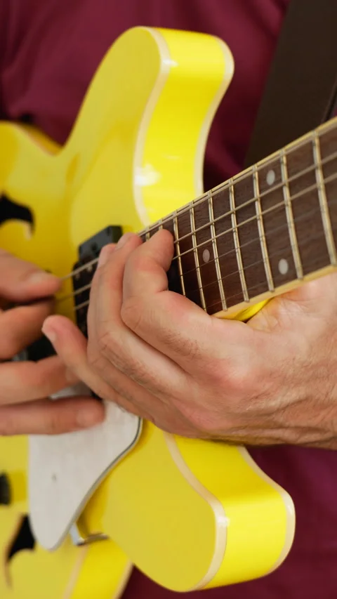 Man playing a yellow guitar, selective focus. No faces shown, vertical video Stock Footage 217730315