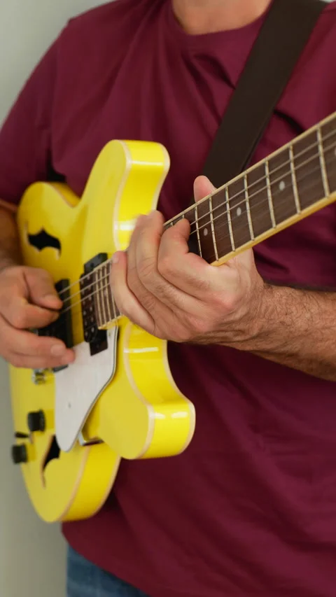 Man playing a yellow guitar, selective focus. No faces shown, vertical video. Stock Footage 217730508