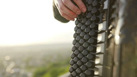A man plays the accordion at sunset with a view of the city. Close up Stock Footage 242428962