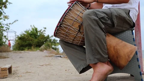 A man plays an African djembe drum against a blue sky. Creativity, rest and rela Stock Footage 116617751