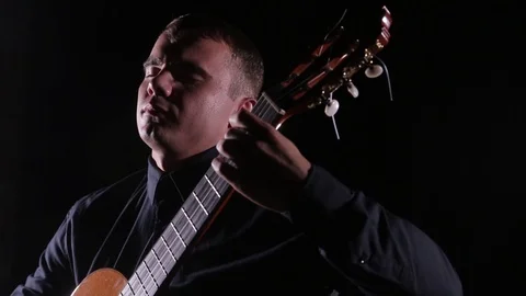 Man plays the classical guitar on a black background,close-up face,isolated Stock-Footage 121583926
