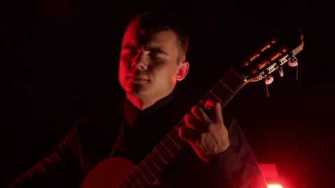 Man plays the classical guitar on a black background, close-up face, isolated 스톡 동영상 121584153