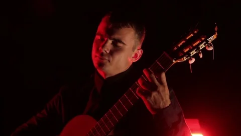 Man plays the classical guitar on a black background, close-up face, isolated 库存影片 121584171