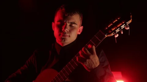 Man plays the classical guitar on a black background, close-up face, isolated Stock Footage 121584186