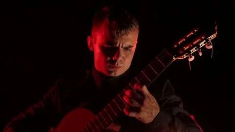 Man plays the classical guitar on a black background, close-up face, isolated Video stock 121584194