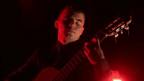 Man plays the classical guitar on a black background, close-up face, isolated 動画素材 121584196