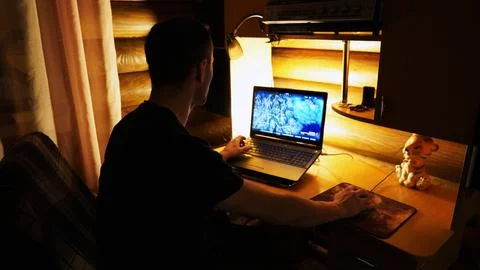 A man plays a computer game on a laptop at home Stock Photos