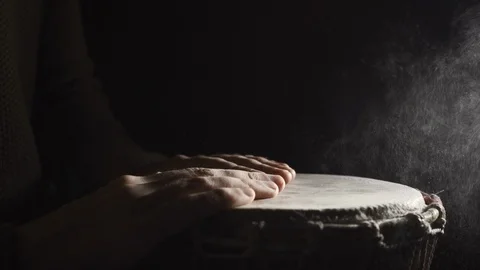 Man plays the djembe drum covered with powder in the darkness, side view, slowmo Stock Footage 114063606